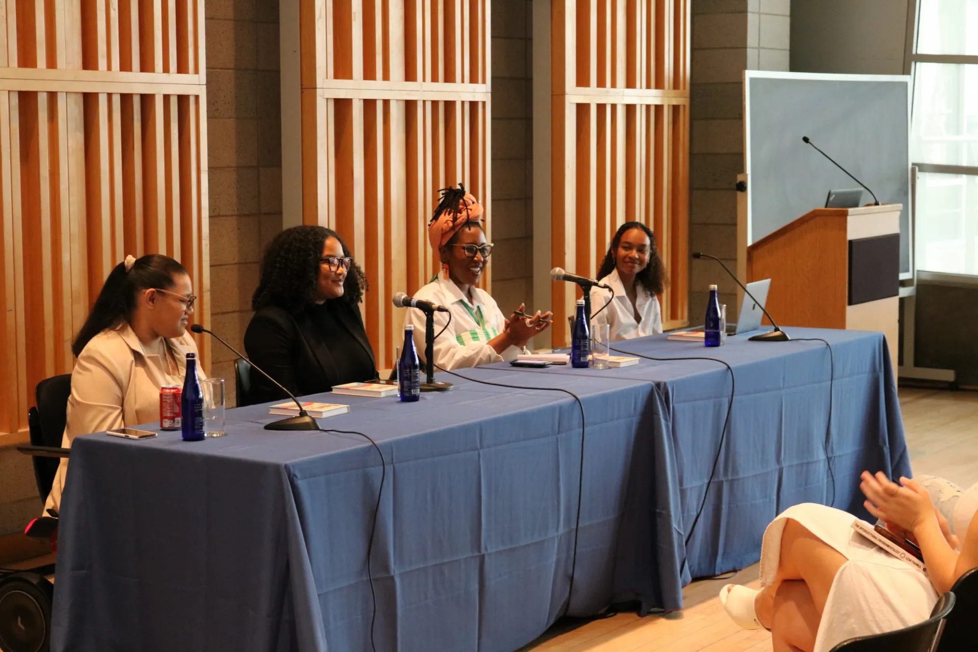 Image of one of the panelist speaking, in a table of 4 people including host 